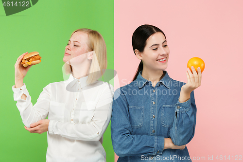 Image of Diet. Dieting concept. Healthy Food. Beautiful Young Women choosing between fruits and unhelathy fast food