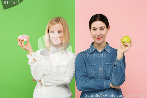 Image of Diet. Dieting concept. Healthy Food. Beautiful Young Women choosing between fruits and unhelathy cake