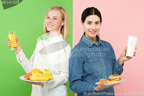 Image of Diet. Dieting concept. Healthy Food. Beautiful Young Women choosing between fruits and unhelathy fast food