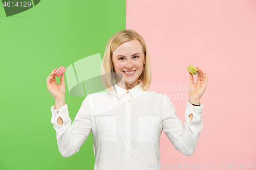 Image of Young beautiful woman holding macaroons pastry in her hands