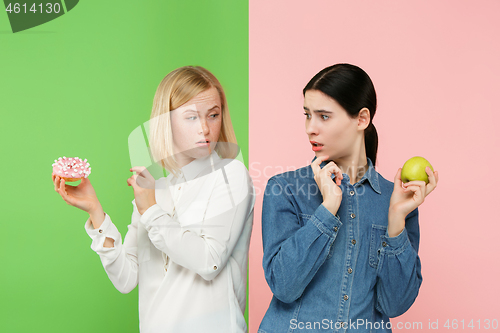 Image of Diet. Dieting concept. Healthy Food. Beautiful Young Women choosing between fruits and unhelathy cake