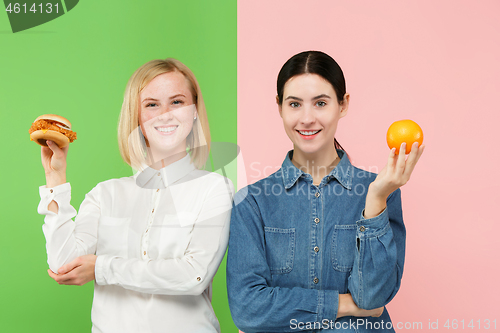 Image of Diet. Dieting concept. Healthy Food. Beautiful Young Women choosing between fruits and unhelathy fast food