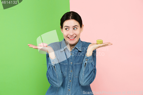 Image of Young beautiful woman holding macaroons pastry in her hands