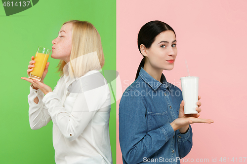 Image of Diet. Dieting concept. Healthy Food. Beautiful Young Women choosing between fruit orange juice and unhelathy carbonated sweet drink