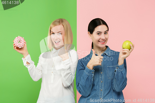 Image of Diet. Dieting concept. Healthy Food. Beautiful Young Women choosing between fruits and unhelathy cake