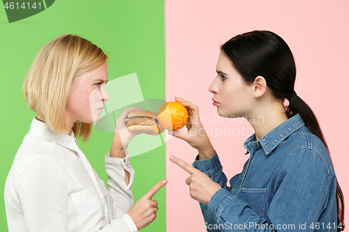 Image of Diet. Dieting concept. Healthy Food. Beautiful Young Women choosing between fruits and unhelathy fast food