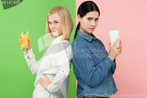 Image of Diet. Dieting concept. Healthy Food. Beautiful Young Women choosing between fruit orange juice and unhelathy carbonated sweet drink