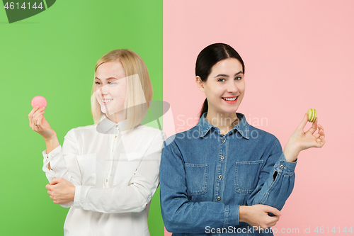 Image of Young beautiful women holding macaroons pastry in her hands