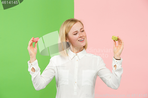 Image of Young beautiful woman holding macaroons pastry in her hands