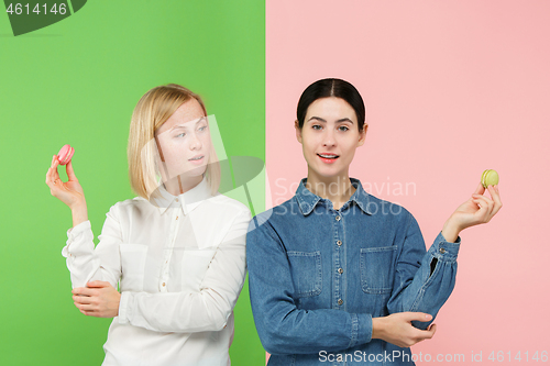 Image of Young beautiful women holding macaroons pastry in her hands