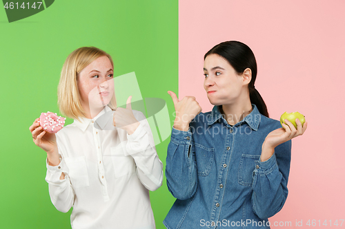 Image of Diet. Dieting concept. Healthy Food. Beautiful Young Women choosing between fruits and unhelathy cake