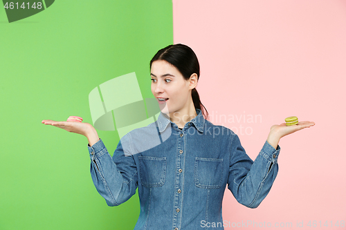 Image of Young beautiful woman holding macaroons pastry in her hands