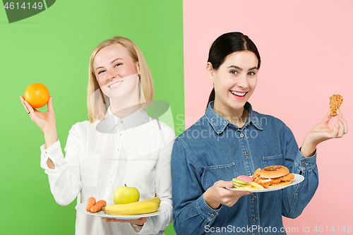 Image of Diet. Dieting concept. Healthy Food. Beautiful Young Women choosing between fruits and unhelathy fast food