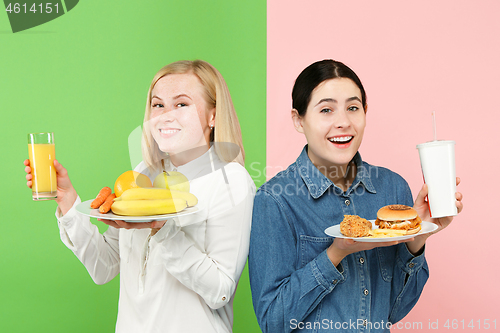 Image of Diet. Dieting concept. Healthy Food. Beautiful Young Women choosing between fruits and unhelathy fast food