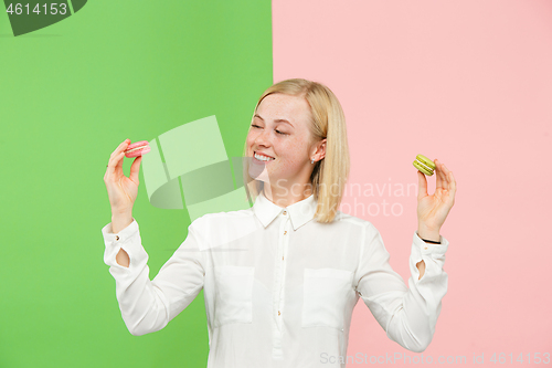 Image of Young beautiful woman holding macaroons pastry in her hands