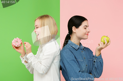 Image of Diet. Dieting concept. Healthy Food. Beautiful Young Women choosing between fruits and unhelathy cake