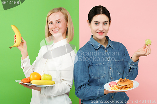 Image of Diet. Dieting concept. Healthy Food. Beautiful Young Women choosing between fruits and unhelathy fast food