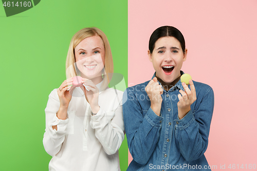 Image of Young beautiful women holding macaroons pastry in her hands