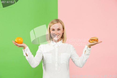 Image of Diet. Dieting concept. Healthy Food. Beautiful Young Woman choosing between fruits and unhelathy fast food
