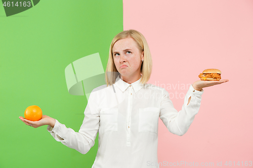 Image of Diet. Dieting concept. Healthy Food. Beautiful Young Woman choosing between fruits and unhelathy fast food