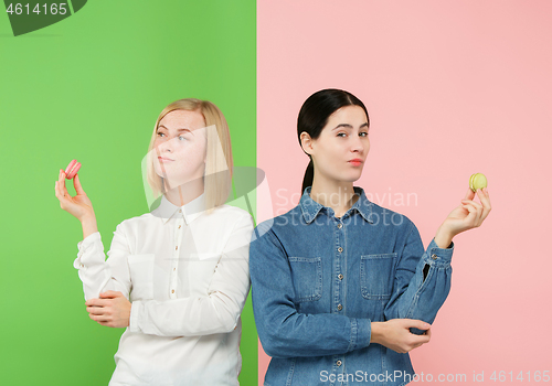 Image of Young beautiful women holding macaroons pastry in her hands