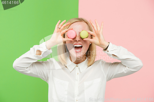 Image of Young beautiful woman holding macaroons pastry in her hands