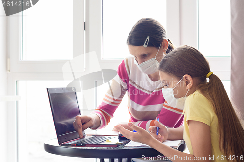 Image of Mom and daughter in self-isolation regime go through online schooling