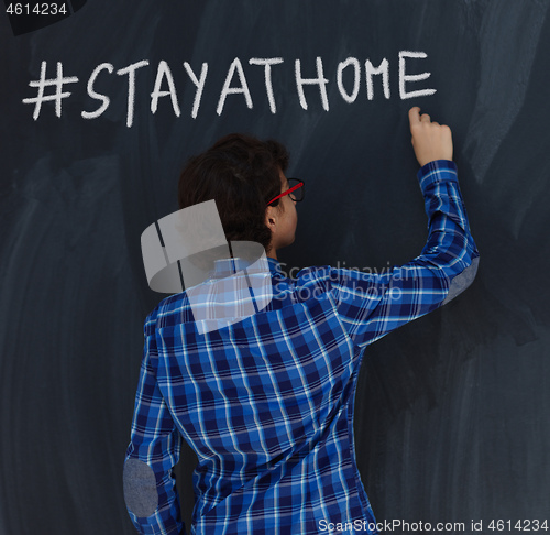 Image of Teen Boy with chalk  writing on black chalkboard hashtag stay at