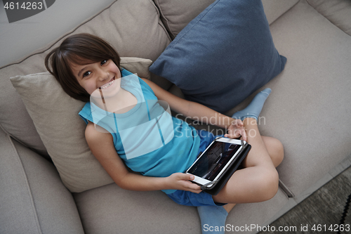 Image of Little Arabian boy sitting on sofa and playing game on digital t
