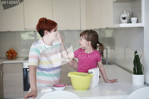 Image of Mother and daughter playing and preparing dough in the kitchen.