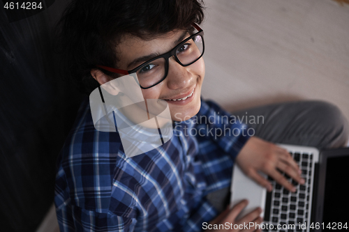 Image of Arab teenager using laptop to work on homework  at home