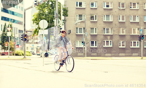 Image of young hipster man with bag riding fixed gear bike