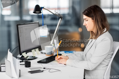 Image of businesswoman with notebook working at office
