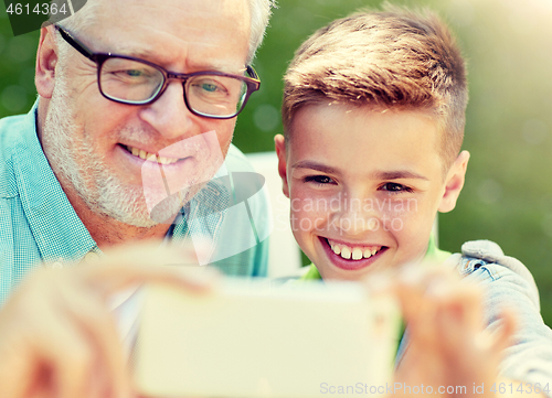 Image of old man and boy taking selfie by smartphone