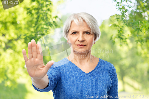 Image of senior woman in blue sweater making stop gesture