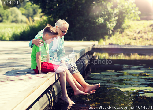 Image of grandfather and grandson sitting on river berth