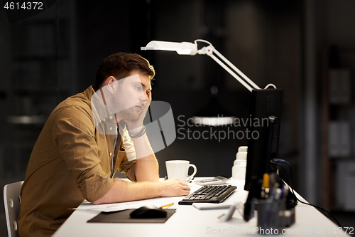 Image of tired or bored man working late at night office