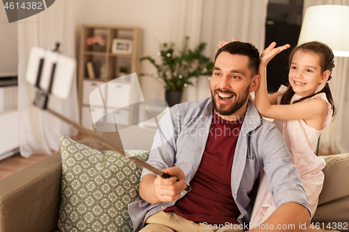 Image of father and daughter taking selfie at home