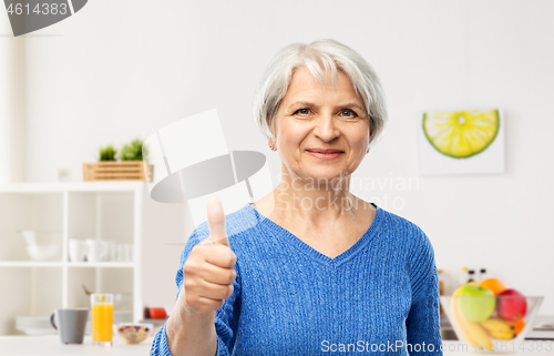 Image of smiling senior woman showing thumbs up in kitchen