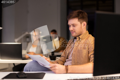 Image of man with papers working at night office