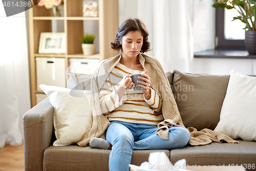 Image of sad sick young woman drinking hot tea at home