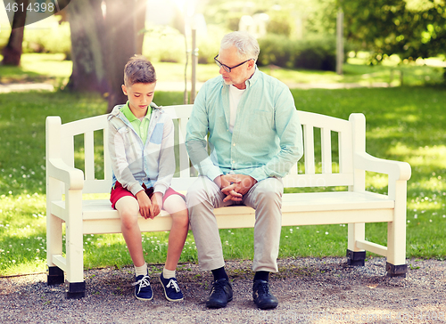 Image of grandfather and grandson talking at summer park