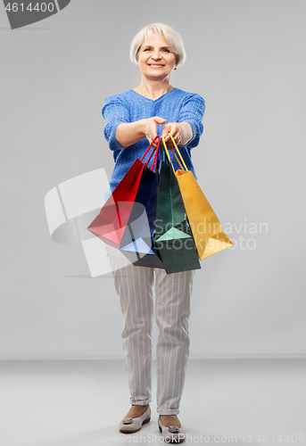 Image of senior woman with shopping bags over grey