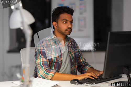 Image of creative man with computer working at night office