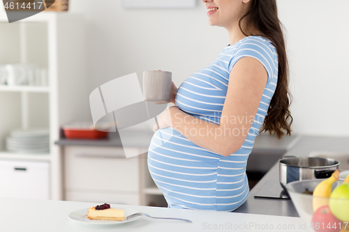 Image of close up of pregnant woman with cup of tea at home