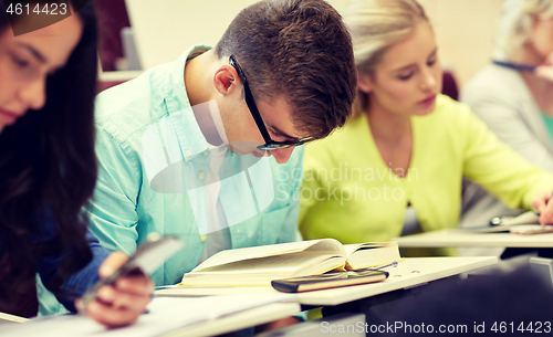 Image of male student in glasses reading book at lecture