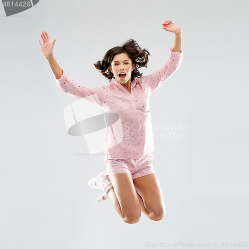 Image of happy woman in pajama jumping high