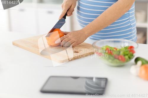 Image of pregnant woman cooking vegetable salad at home