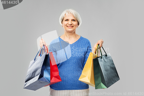 Image of senior woman with shopping bags over grey