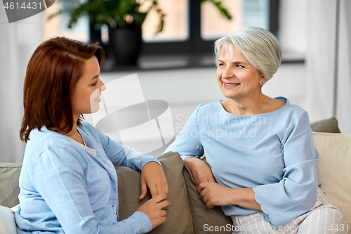 Image of senior mother talking to adult daughter at home